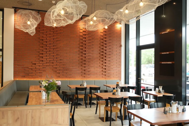 Restaurace U Radnice s cihlovou stěnou a dřevěnými stoly.